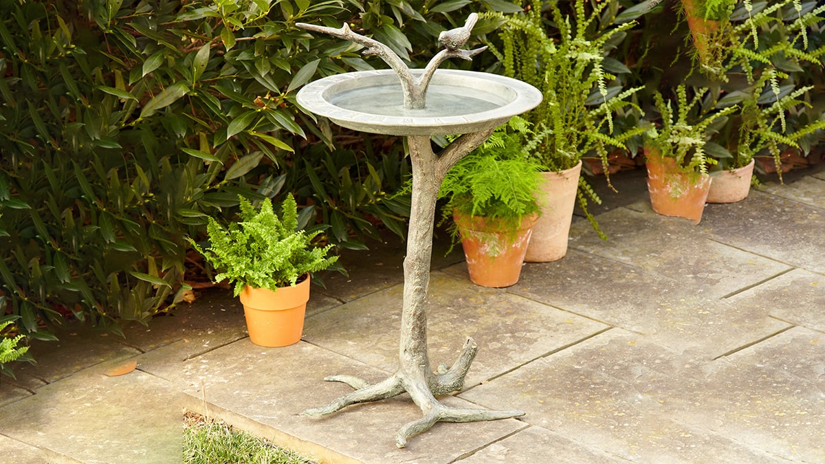 A beautiful bird bath in the middle of the garden made of wood and cement.