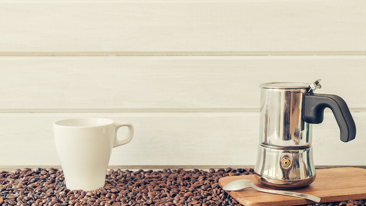 A coffee maker with a mug an spoon