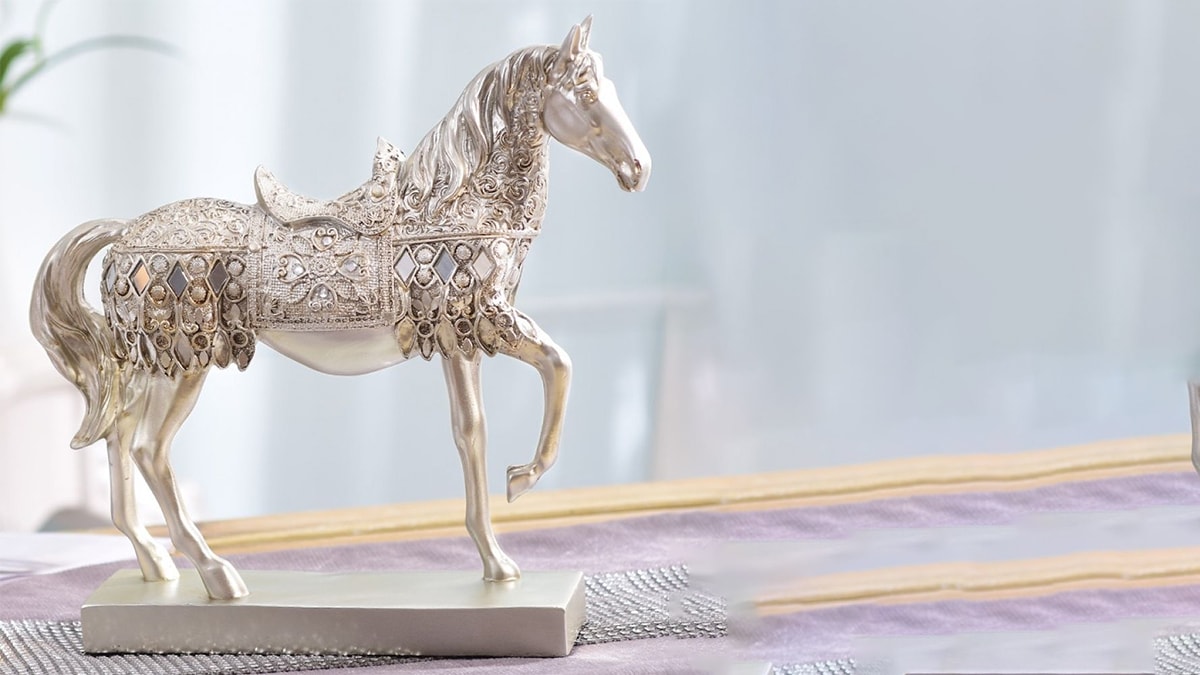 An ornament of a horse that is made of silver and has one leg up in the air.
