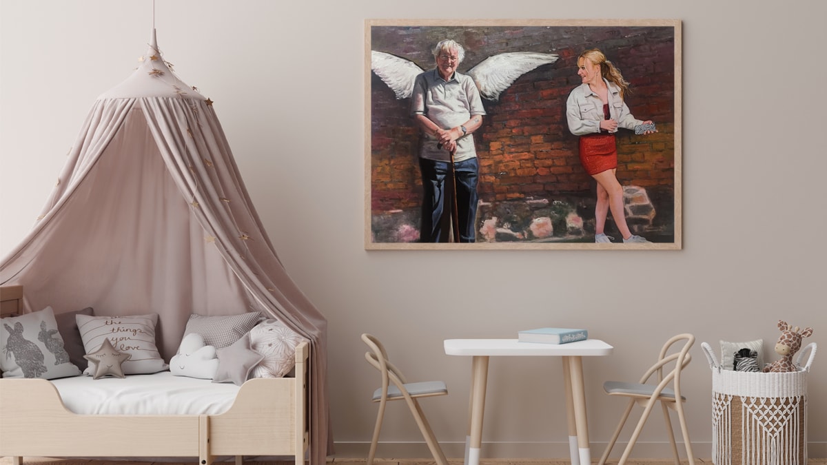 A handmade custom portrait of a girl and her grandfather who has passed away and has wings drawn around him as a sign of an angel. It is on a wall ad there are chairs and a table surrounding it.