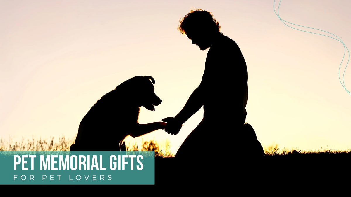 A photo of a man holding the paw of his dog. The text reads pet memorial gifts for pet lovers.