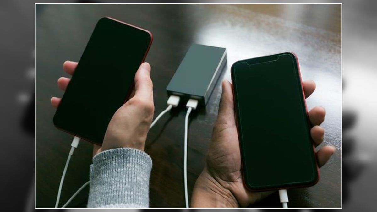 Two hands holding phones connected with portable chargers. This is one of the graduation gift ideas for grandson. 