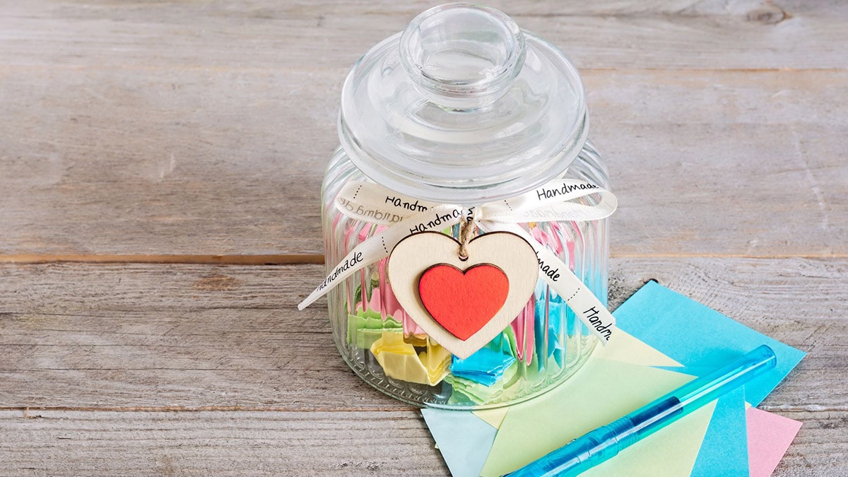 A decorated jar with a lid that is filled with positive notes. 