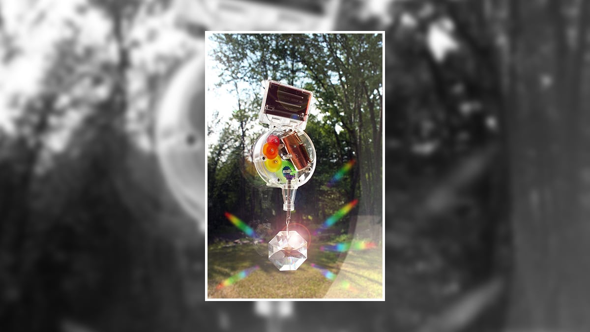 A Rainbow maker hung inside a window  and is reflecting rainbow lights, 
