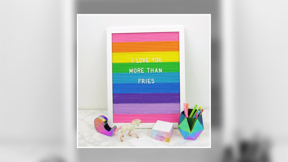 a handmade rainbow letterboard with  text "I Love You More Than fries" written on it. 
