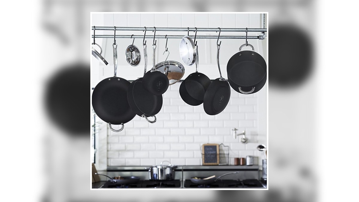 black colored pots and pans hung on above kitchen counter. 