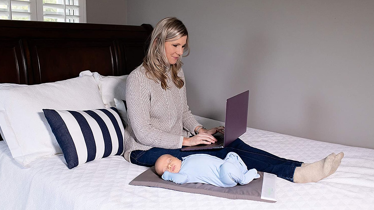 a mom is working peacefully on her laptop as a baby sleeps on vibrating pad. 