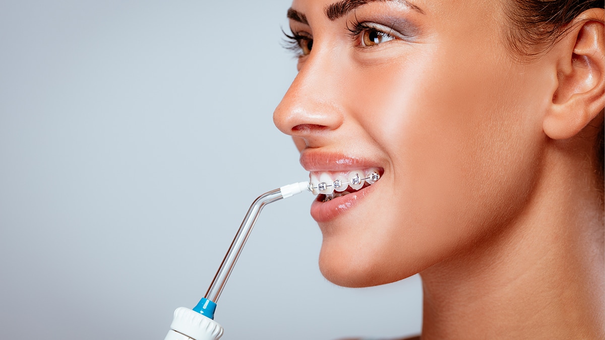 a woman cleaning her teeth with a water flosser