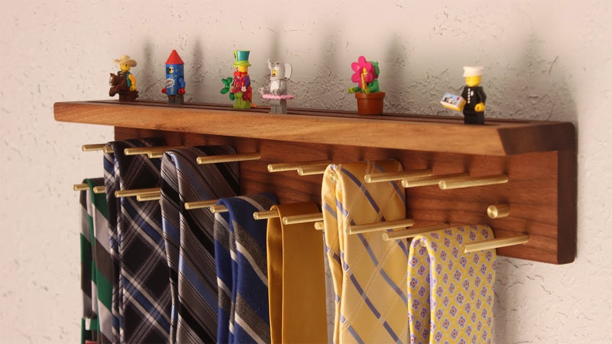 A wooden tie rack that has tie's in different colors and fabrics hanging on it