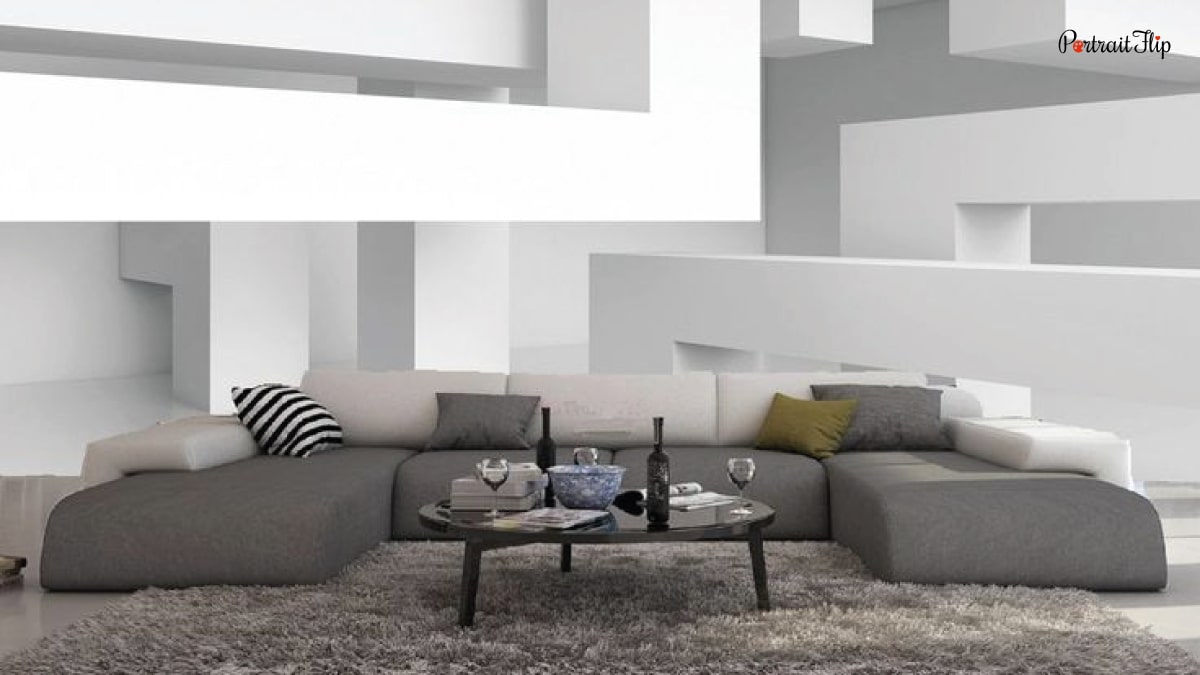 An interior of a house with a wall full of 3D art. It is a living room trend in 2022. Sofas that are grey and white in color. There is a table in the middle.