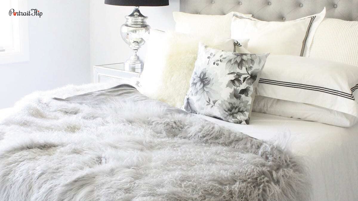 A bed with fuzzy throw blankets that are white in color and there are pillows all around. A bedroom decorating trend .