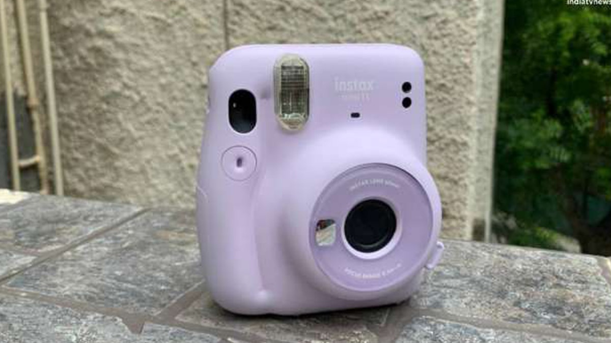Instax mini 11 camera in purple color placed on a tiled wall.