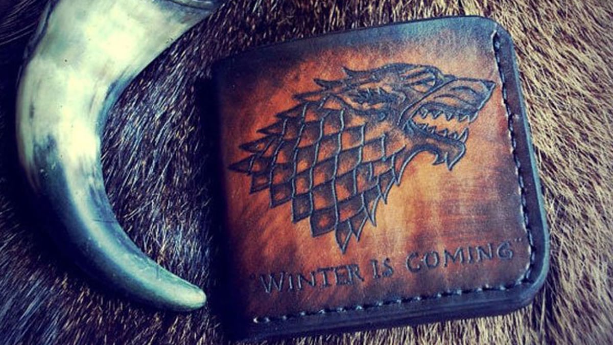 A customized quirky wallet with a wolf print on it inspired from game of thrones. the text on the wallet reads winter is coming.
