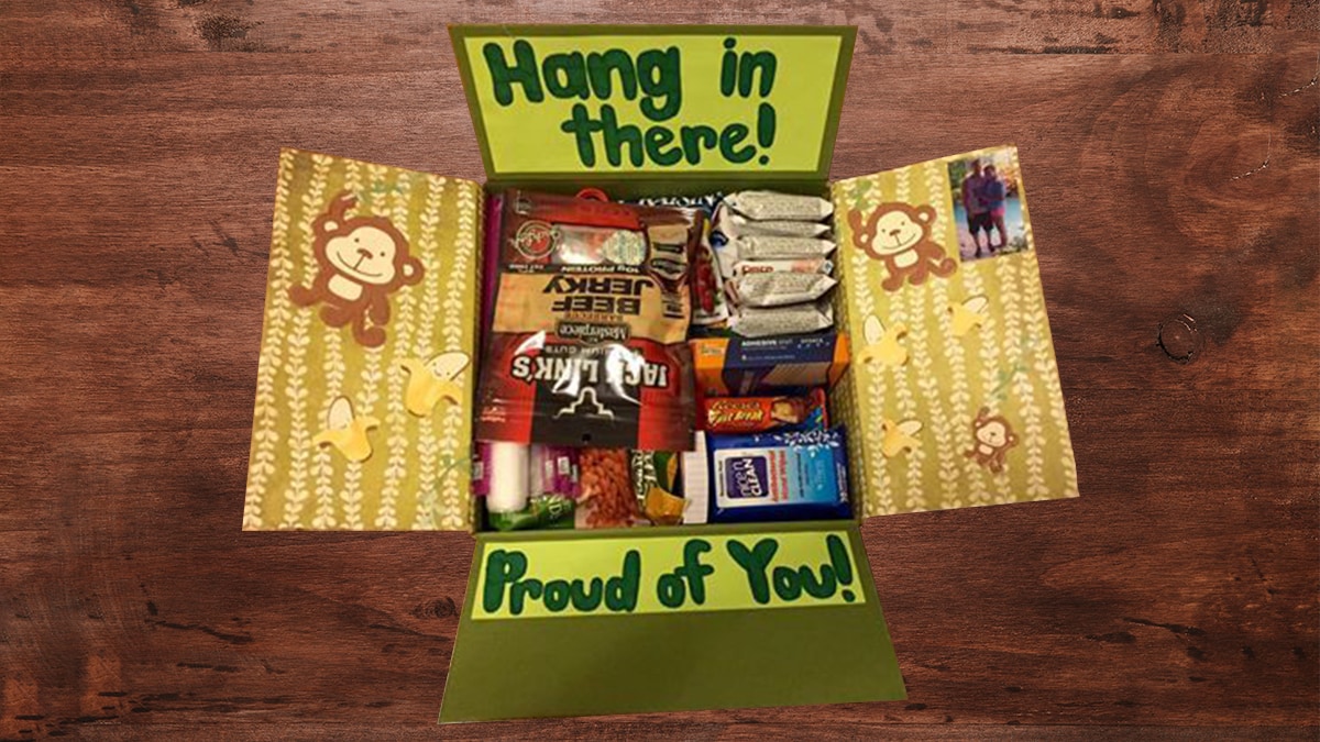 A military care package with lots of snacks and games and a note that says 'proud of you'