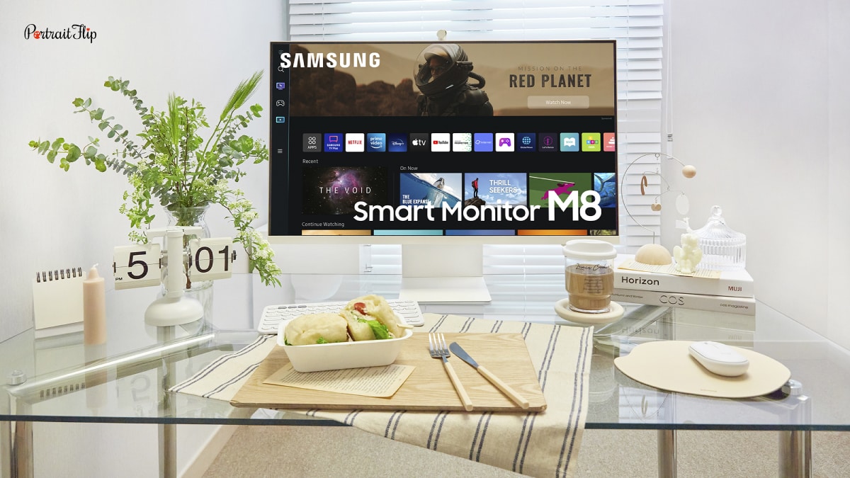 An image of a smart desktop on a table. There is food around the table. This is another trends in home decor 2022. That is smart gadgets and technology.