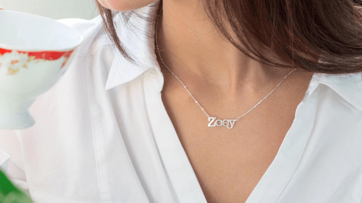 A pet name necklace worn by a woman in the neck shown as a sympathy gift idea to be given to someone who has lost their pet.
