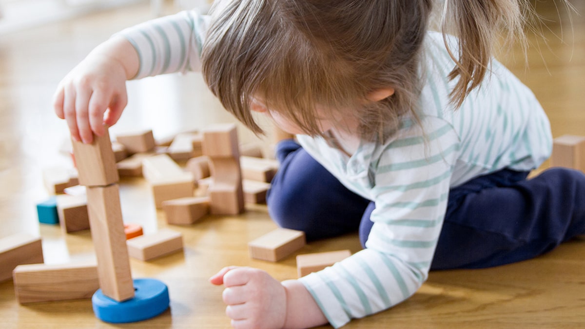 a small girl playing with wooden blocks