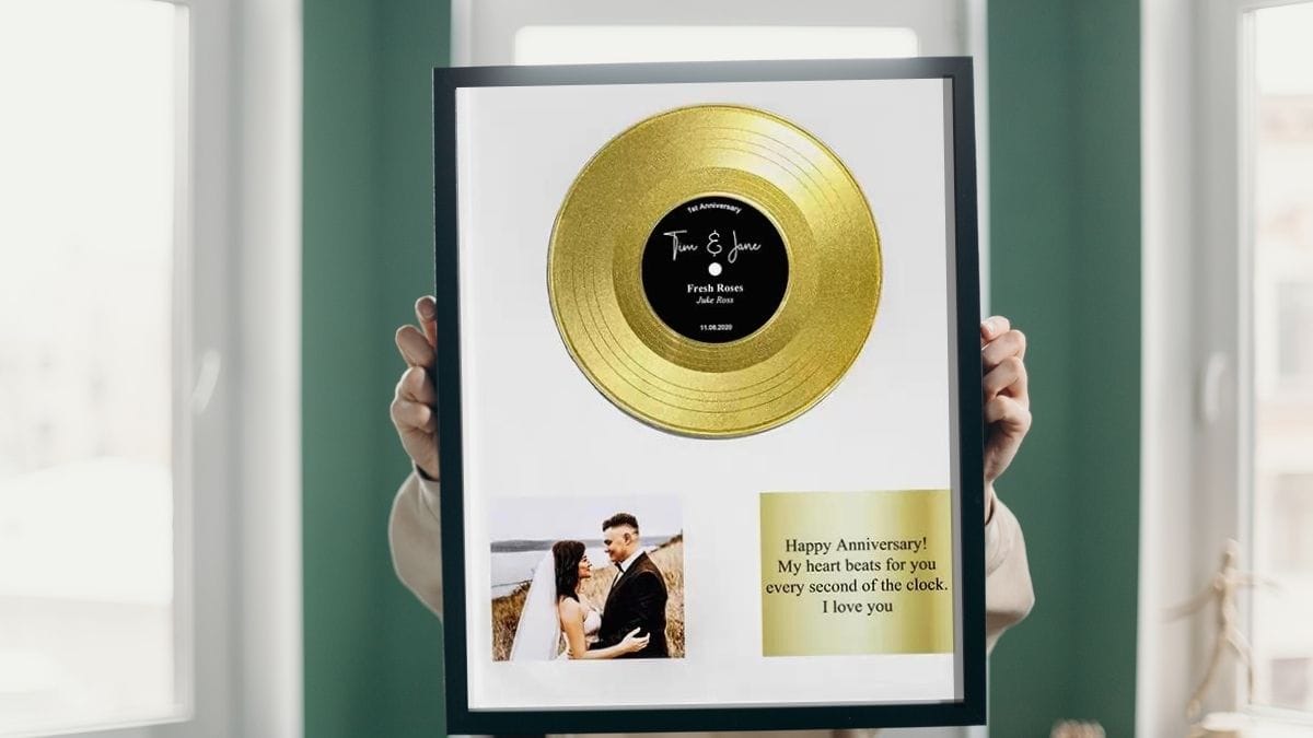 a gold toned vinyl meant framed and held by a woman that was given to her as an anniversary gift