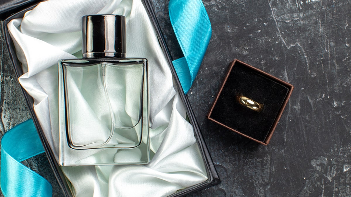 a perfume and its box on a black textured surface