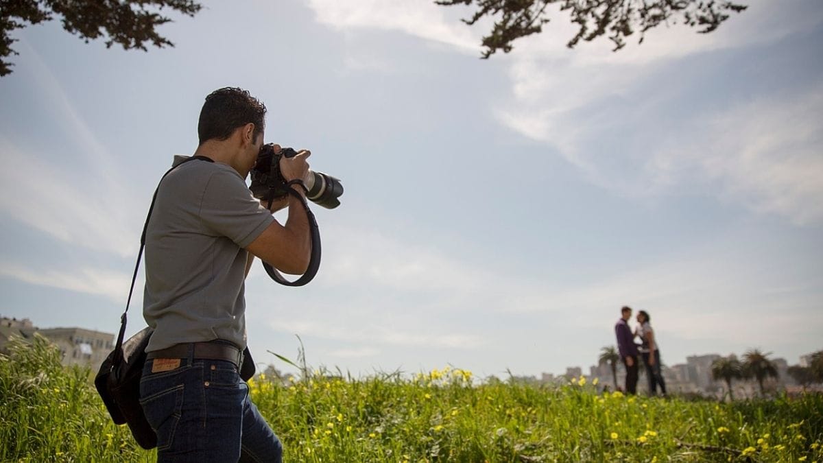 a photographer doing a photoshoot of a couple ho is standing in a field