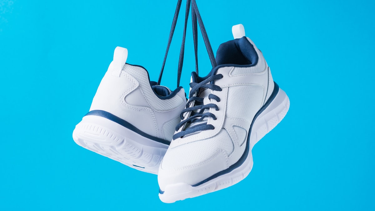 A pair of running shoes hanging in a blue background