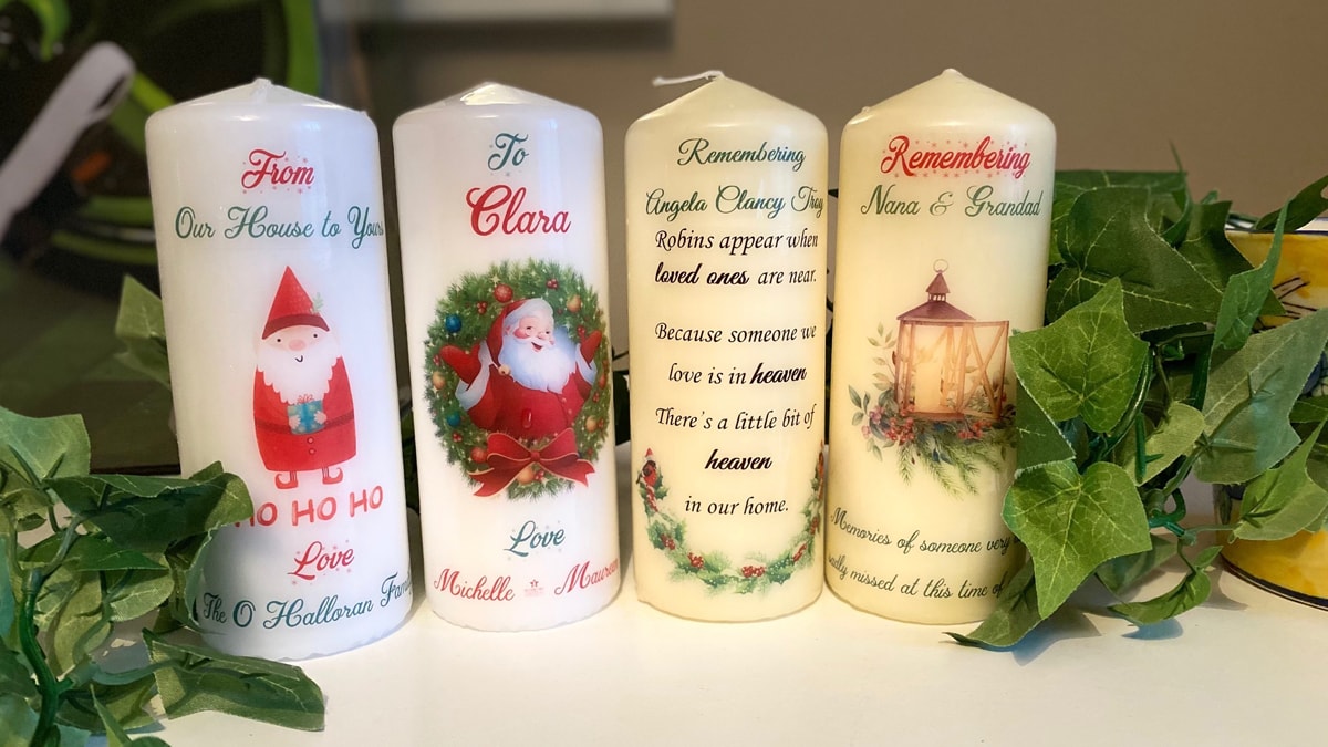 Christmas candles customized with special messages placed on a white table.