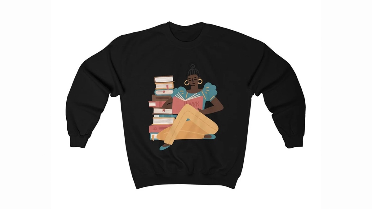 a sweatshirt with an illustration of a girl reading a book