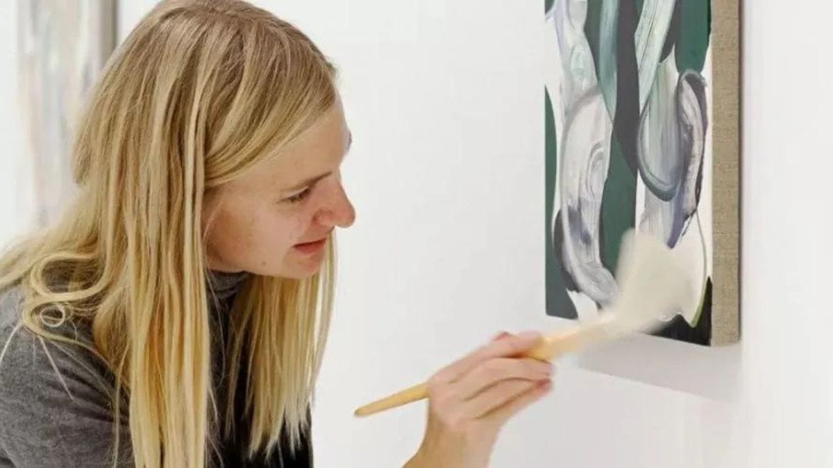 a lady shown dusting an oil painting to prevent it from getting dirty in the first place.