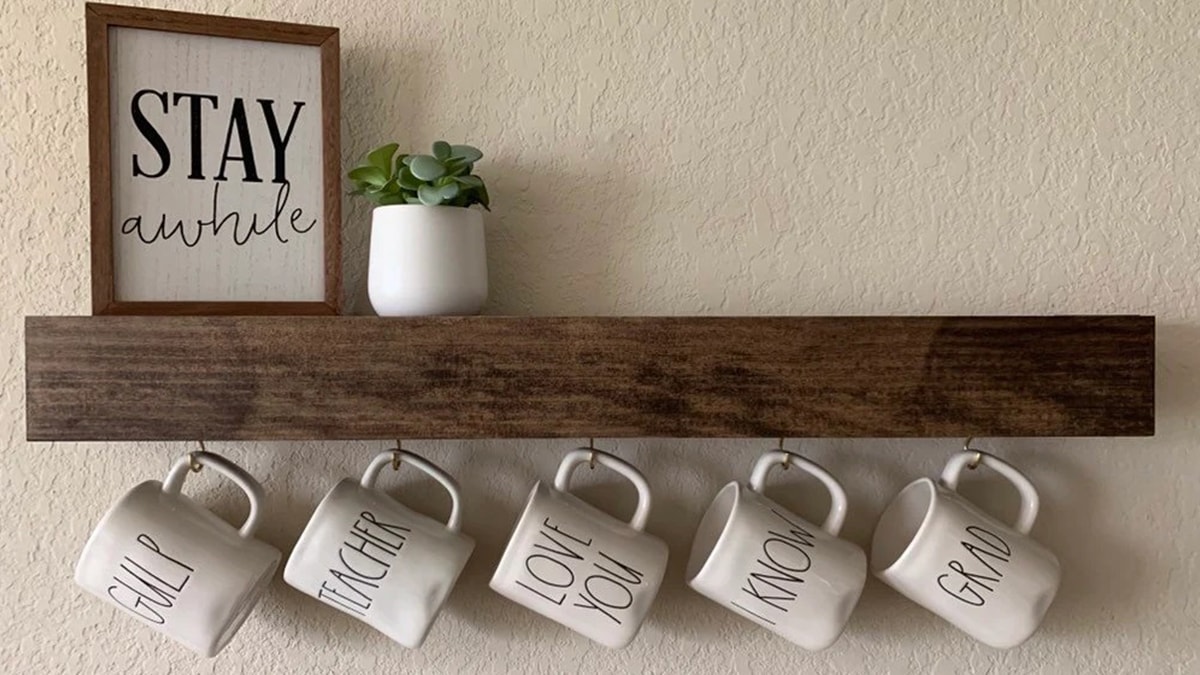 White ceramic mugs hanging on a creative mug shelf.
