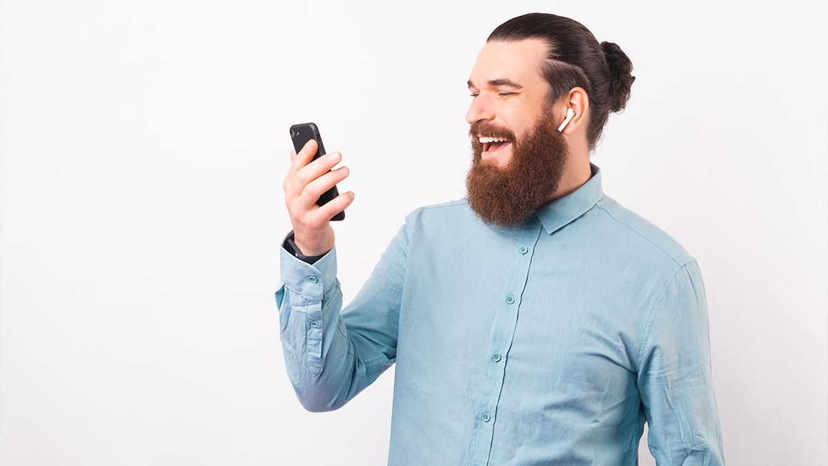 Laughing man looking at his phone while wearing airpods