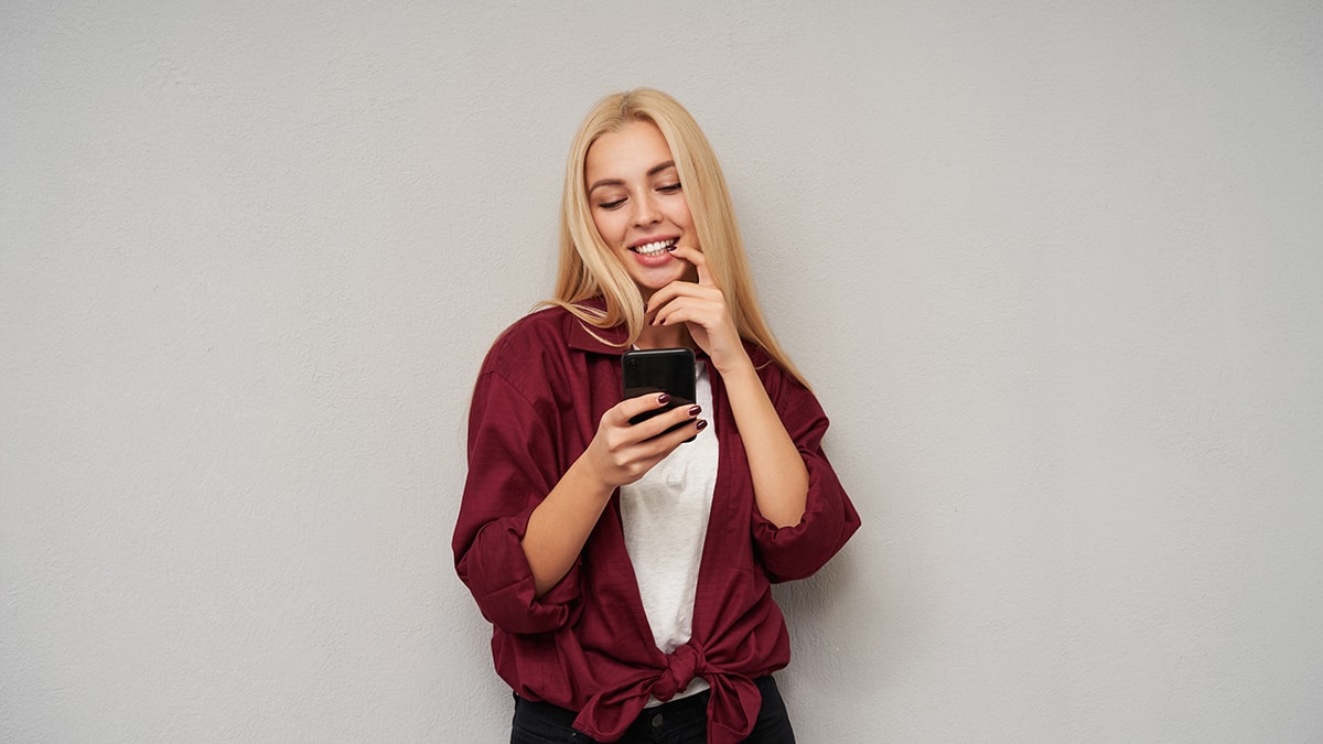 Girl wearing a baggy t-shirt while looking at her phone and smiling