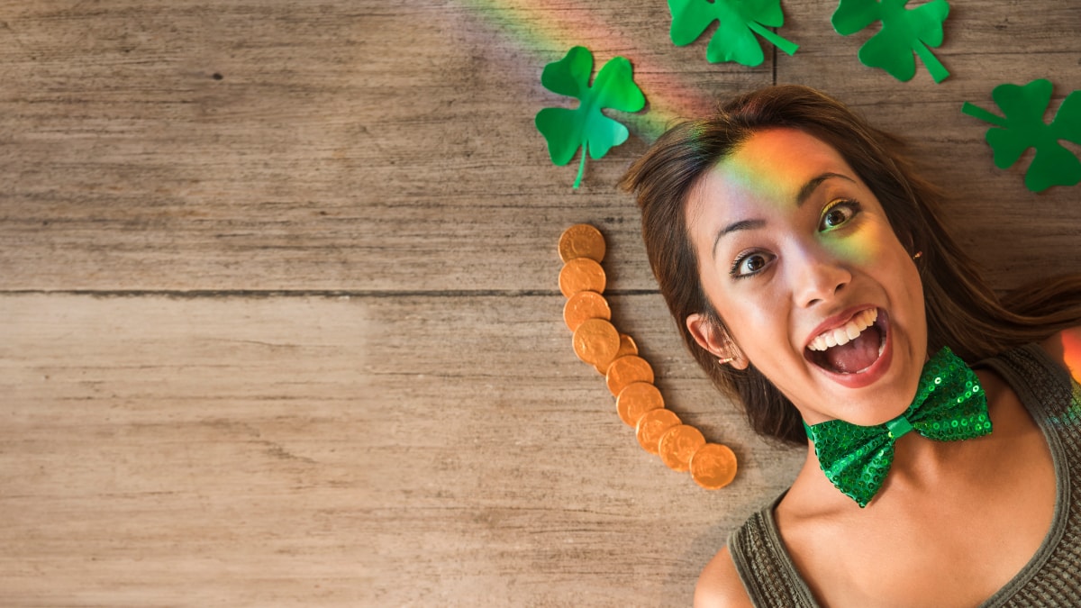 A woman lying on a wooden table with green bow tie and clover leaf around her head