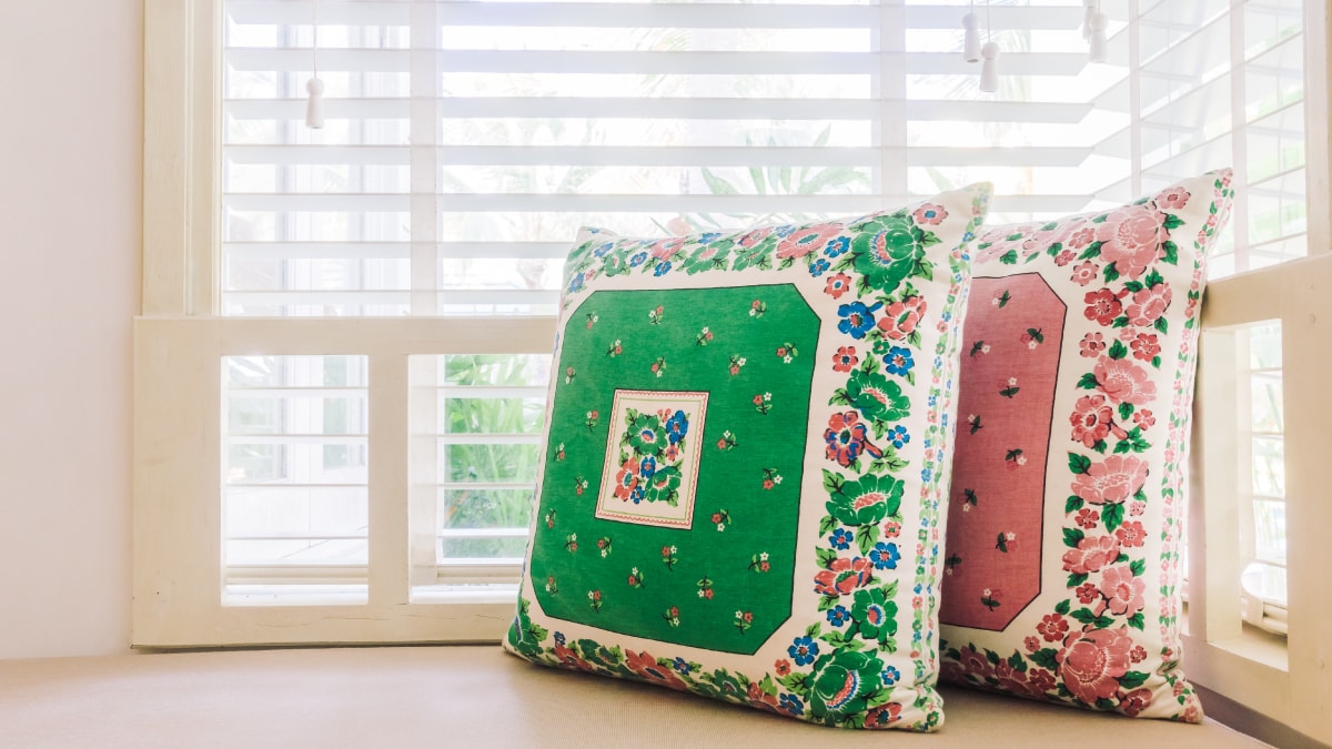 Two embroidery cushion cover placed beside a window