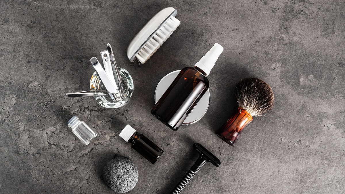 Grooming kit that includes, a nail cutter, two small and one spray bottle, brush, razor on a concrete background