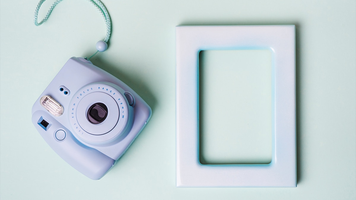 Instant camera with a empty frame in a sea green background