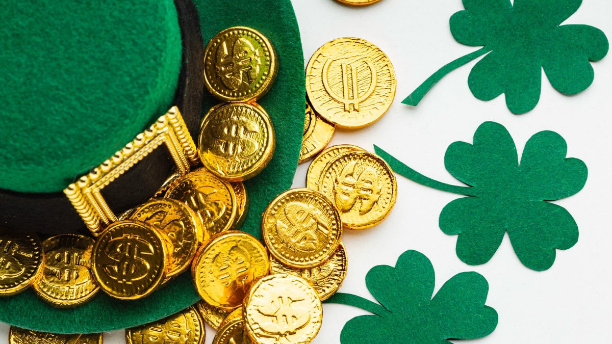 Lucky penny placed on green hat and clover leaf 