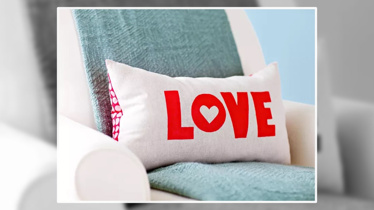 A rectangular shape cushion with a text love placed on a sofa