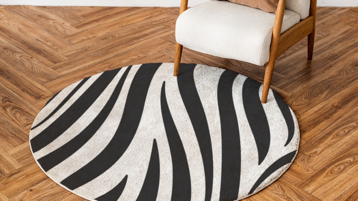 A black and white rug kept on a wooden floor below a sofa