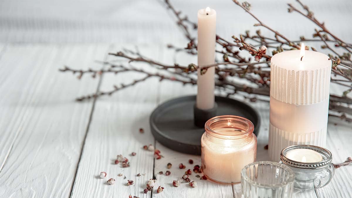 Scented candles placed on the table with branch stems behind it 