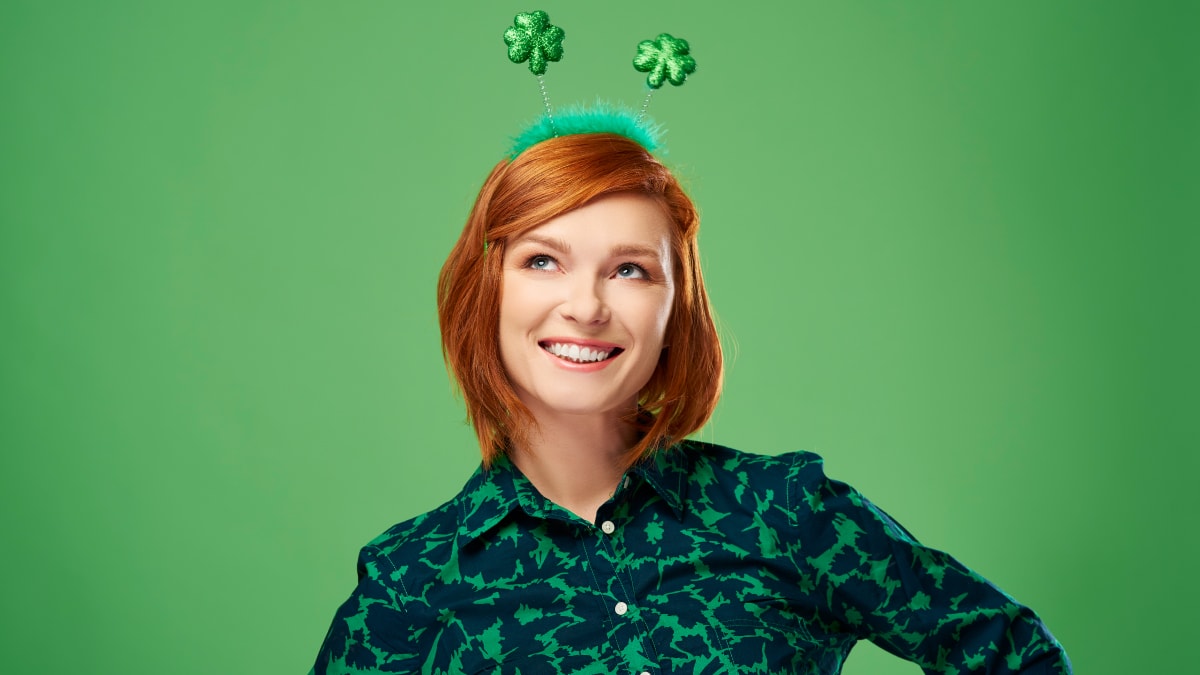 A woman wearing shamrock headbands standing in a green background