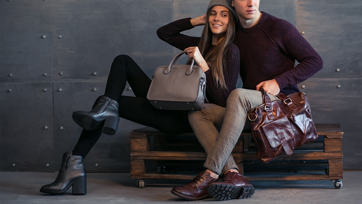Couple sitting on a wooden bench with leather bags and winter boots 