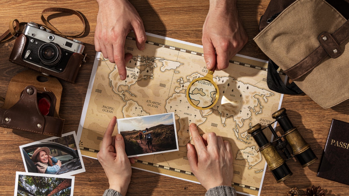 A treasure map with camera, binoculars, and some pictures place on a wooden table 