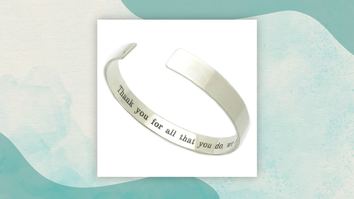 A metal wrist band with a message " Thank you for all that you do" written on it's inner side in a white background as gifts for long distance relationships. 