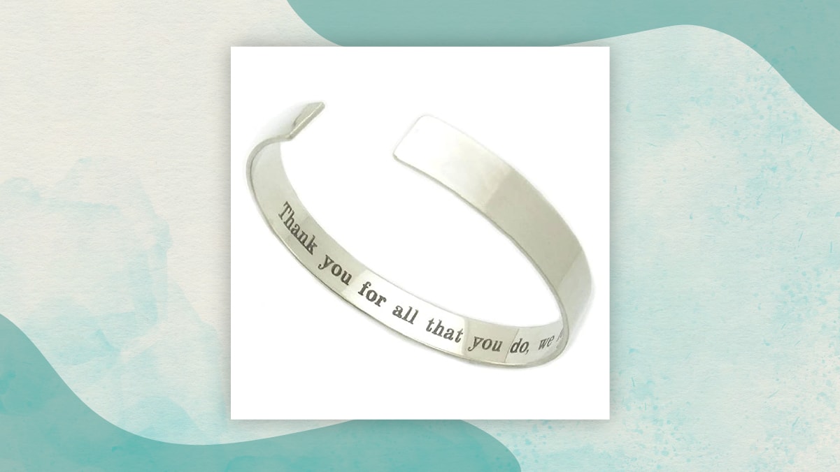 A metal wrist band with a message " Thank you for all that you do" written on it's inner side in a white background as gifts for long distance relationships.
