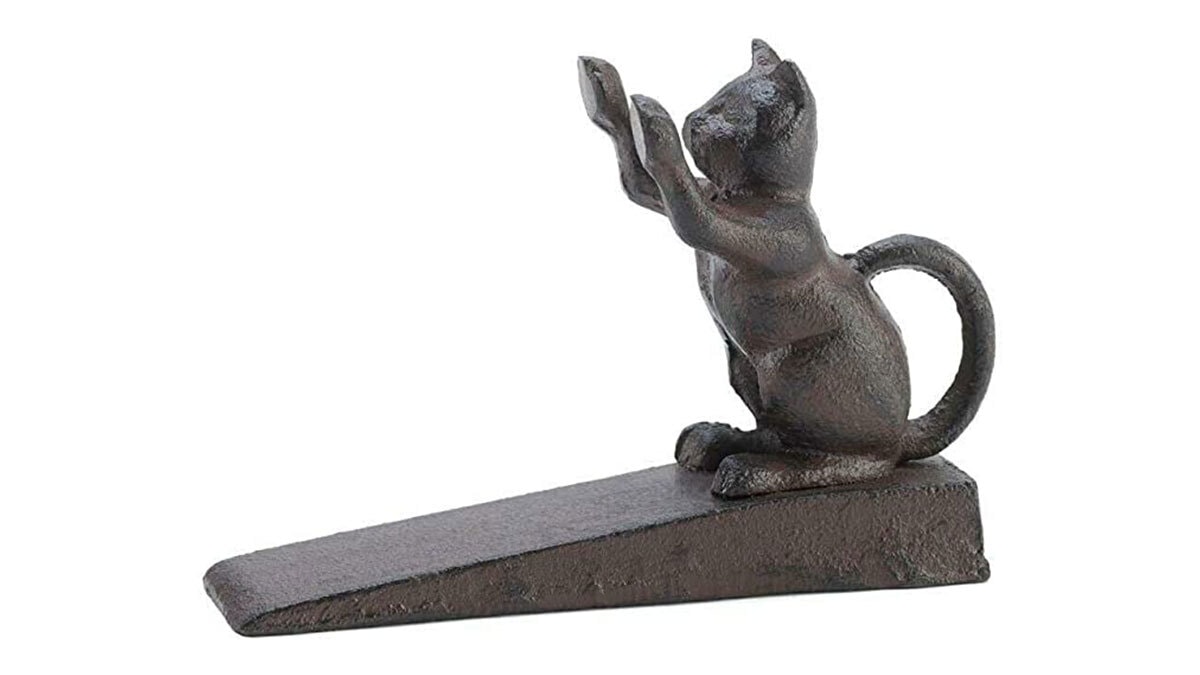 A cat shaped metal cat door stopper on a white background. 