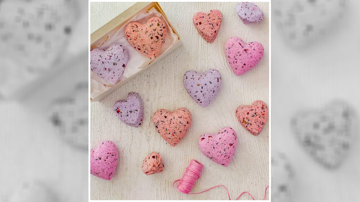 Small heart-shaped multi color bath bombs kept on a wooden table. 