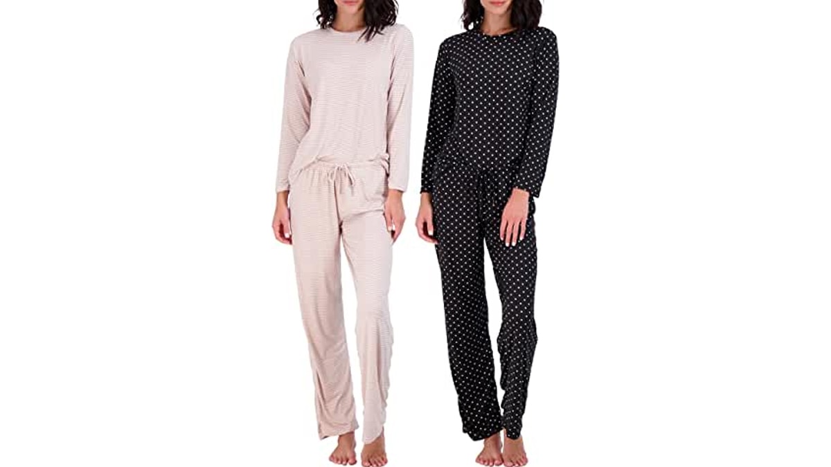 Two women wearing black and off-white pajamas standing in a white background. 