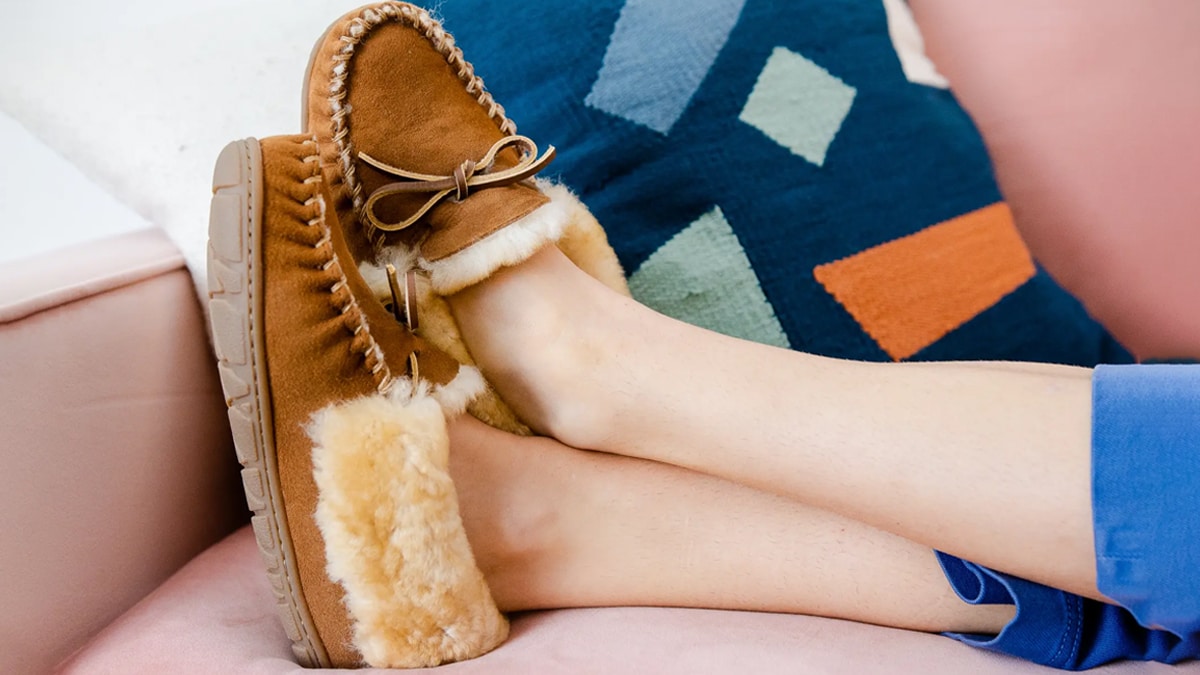 A women wearing brown furry shoes as lying on a pink sofa thinking about bets mother's day gift ideas. 