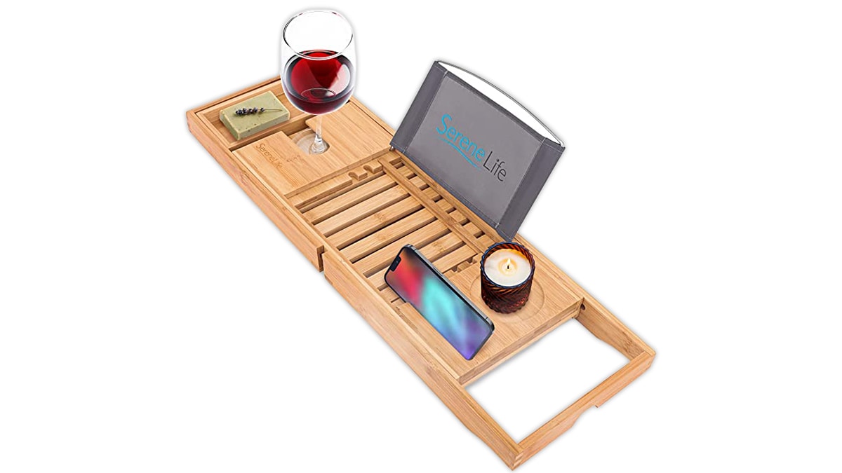 A wooden tub caddy with a phone, a candle a screen and wine glass kept on it as mother's day gift ideas. 