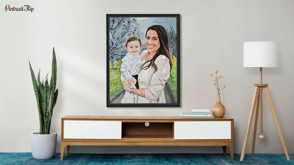 A mother and baby portrait hung on a wall above a wooden cabinet beside a lamp and a pot. 
